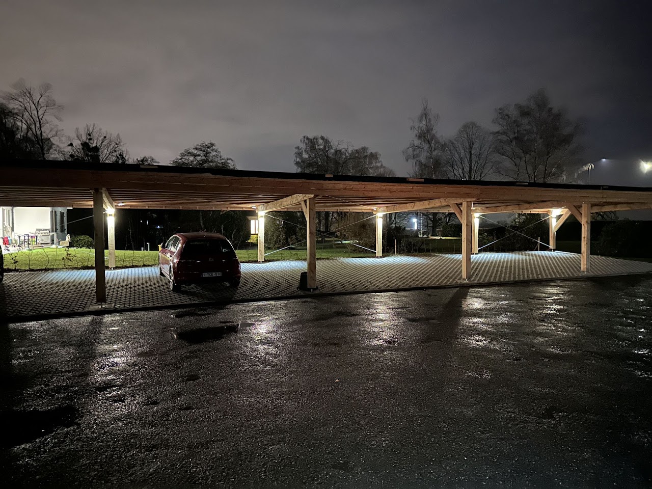 Parking couvert sous carport bois illuminé la nuit, Domaine de la Chênaie Condroz