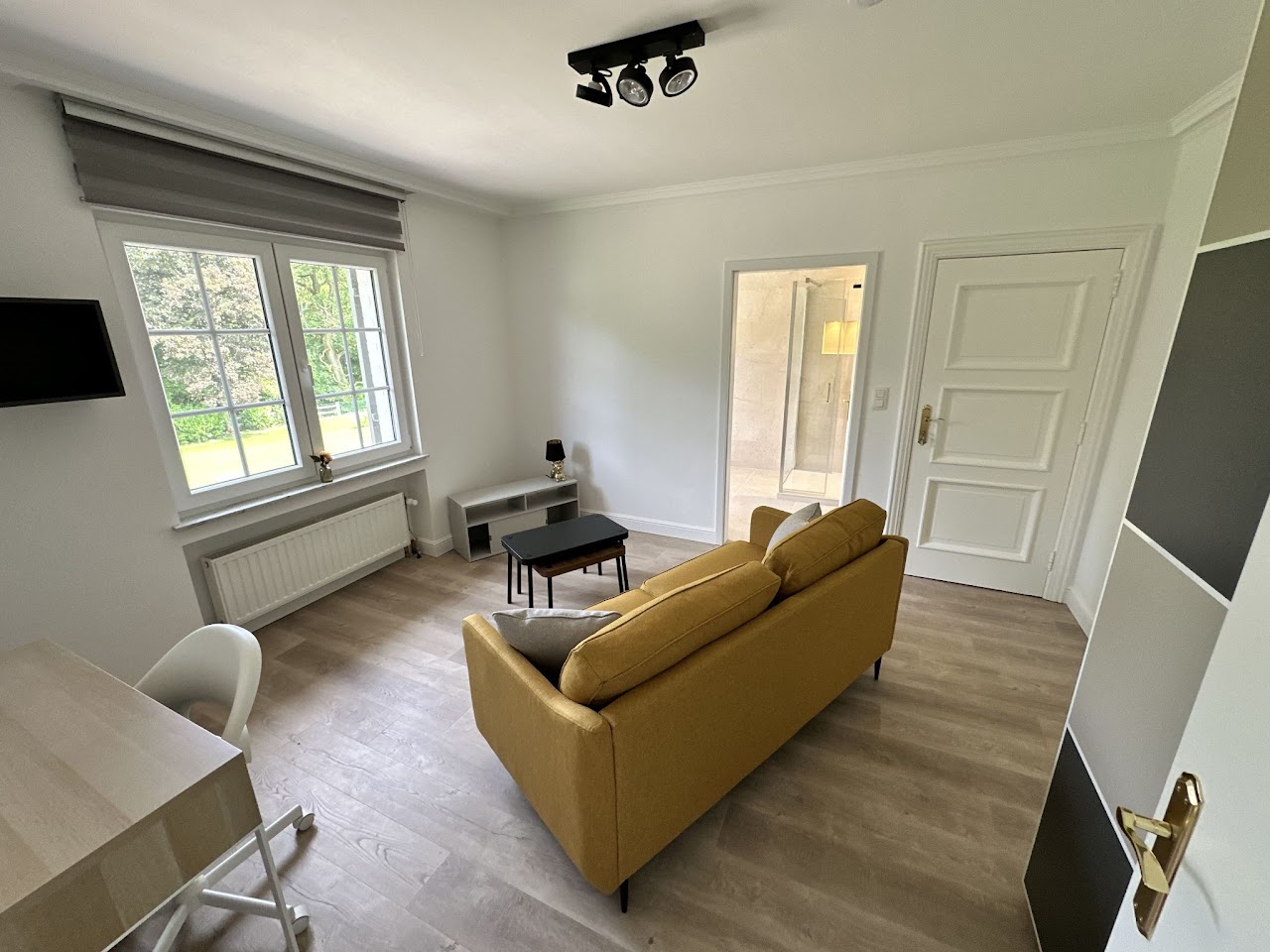 Suite privative avec canapé jaune moutarde et accès salle de douche, coliving Condroz