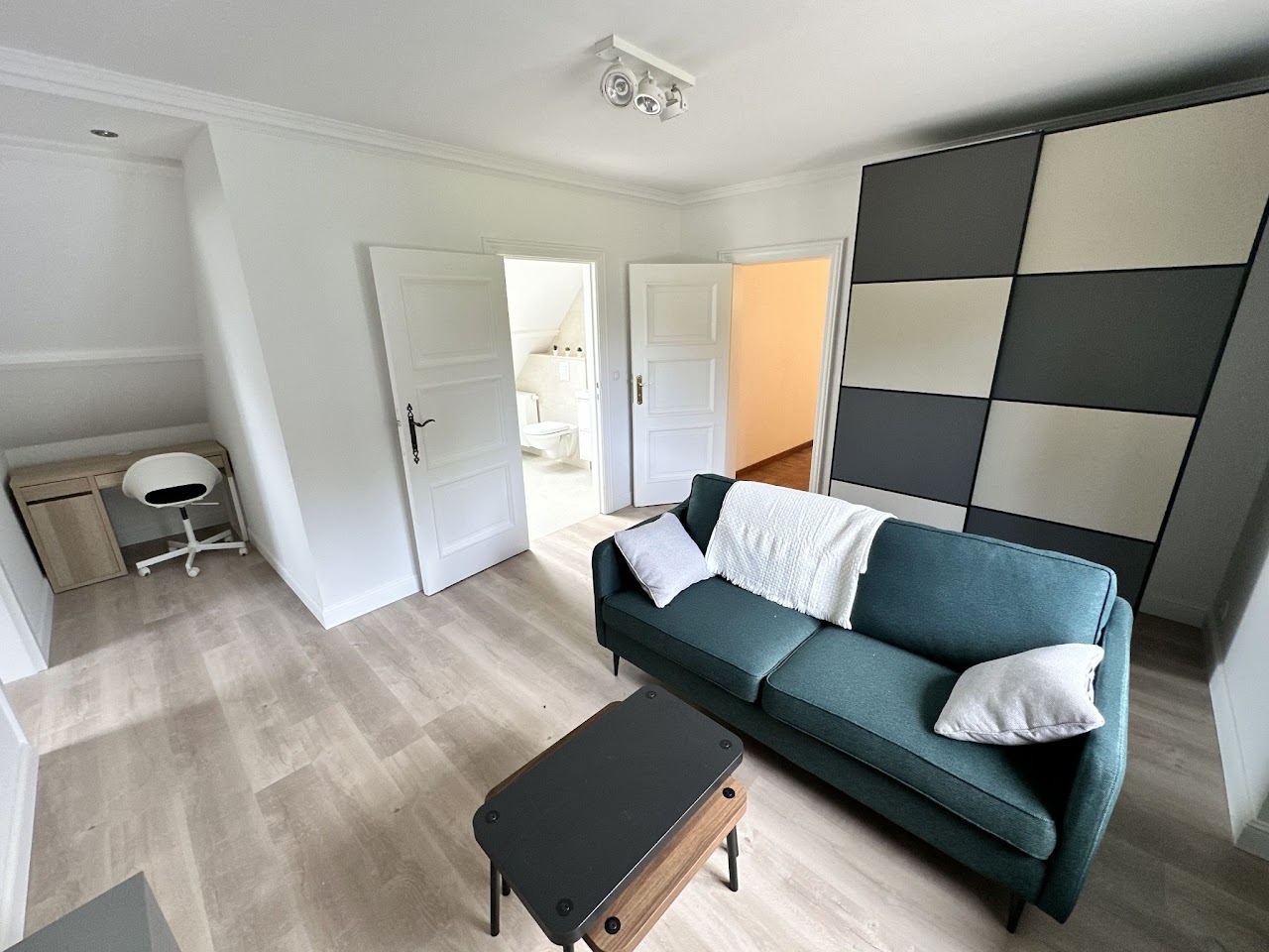 Suite privative avec canapé vert et espace bureau, villa coliving Condroz Belgique